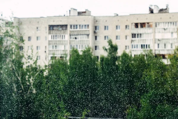 Bulutlu arka planda cam yüzeyine yağmur damlaları düşer. Bulutlu arkaplanda izole edilmiş doğal yağmur damlaları deseni.