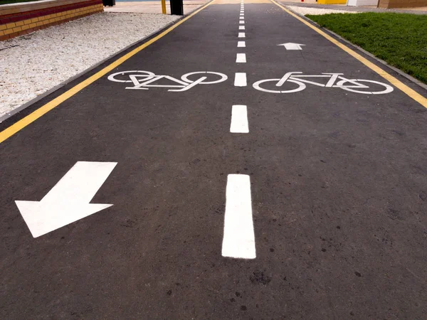 Señal de bicicleta blanca con flecha en el asfalto, señal de carretera en bicicleta en la calle, señal de carril bici en la calle, fondo gris Fotos De Stock