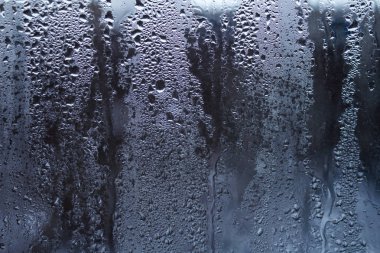 Gökyüzü bulutlu arka planda pencere camları üzerine yağmur damlaları 