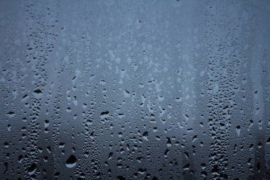 Gökyüzü bulutlu arka planda pencere camları üzerine yağmur damlaları 