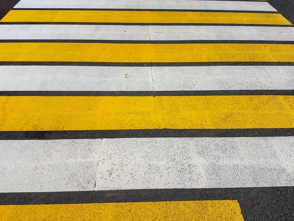 Crosswalk. White and yellow stripes at a pedestrian crossing.