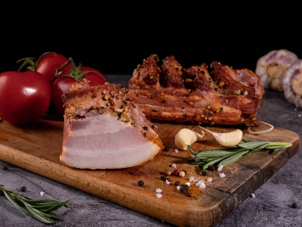 Tasty smoked ham on a wooden board with spices.