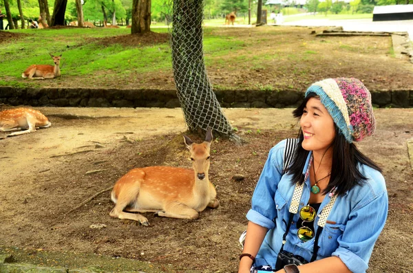 Viajero tailandés mujer sentada y posar para tomar una foto con ciervos a —  Fotos de Stock