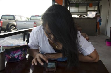 Taylandlı kadınların oynamak ve smartphone cep telefonu ile restoranda sohbet 