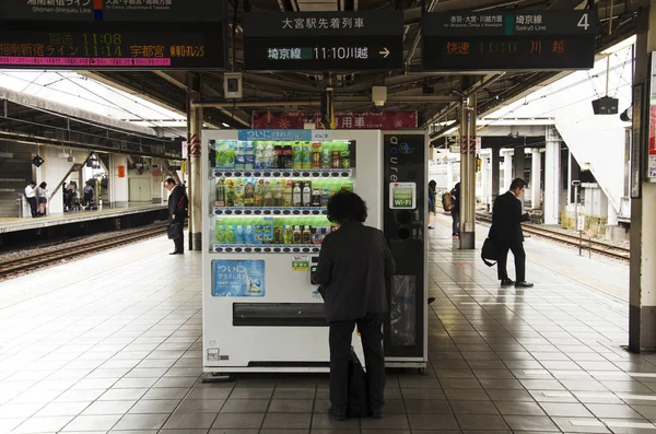 日本の古い女性が自動販売機にコインを挿入します。 — ストック写真