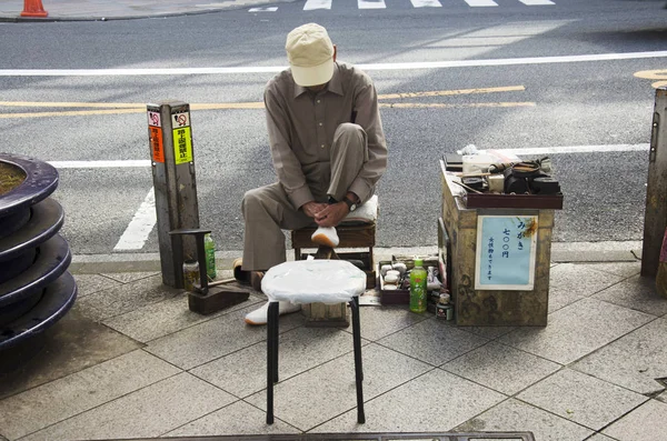 Japonés ancianos servicio reparación zapatos en camino al lado tr — Foto de Stock