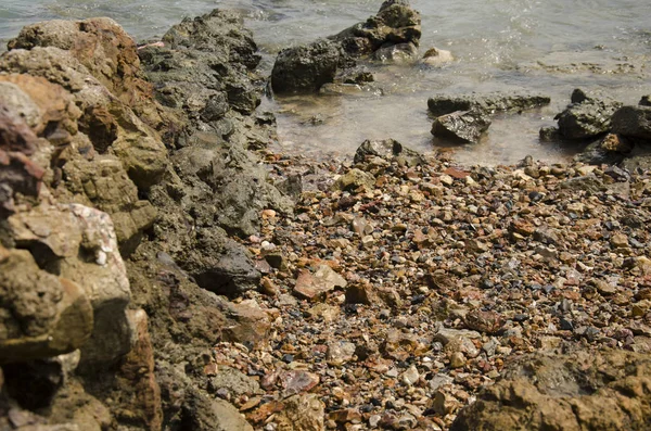 Движение водной волны в море с каменным пляжем и раковиной — стоковое фото