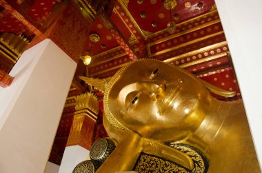 Big golden reclining buddha statue in ubosot or chapel at Wat Pa clipart