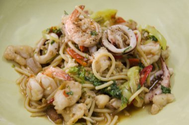 Spagetti kızarmış biber ile baharatlı karışık deniz ürünleri ve fesleğen yaprağı