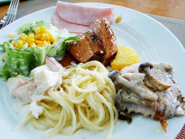 Спагетти, салат, сиденье и ветчина на тарелке — стоковое фото
