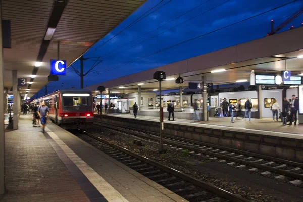 As pessoas caminham e esperam com o trem correndo no terminal para enviar e — Fotografia de Stock