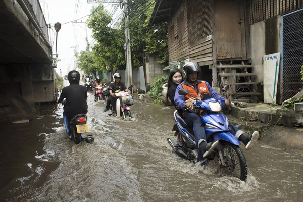 Motorcycle Taxis and volunteer carrying people passed flood on the road go to Bang pai temple Stock Picture