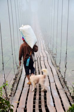 Tay insanlar asma ahşap köprü üzerinde yürüyen çuval taşıma