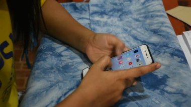 BANGKOK, THAILAND - 26 Mart 2020 'de Tayland' da Bangkok, Tayland 'daki evinde çalışan Taylandlı kadın cep telefonu kullanıyor.