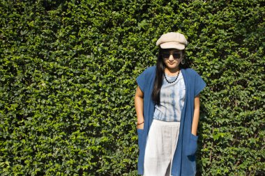 Taylandlı bir kadın modadan çivit giysiler giyer, dışarıda ve bahçede fotoğraf çektirmek için poz verir. Tayland, Nonthaburi 'de bitki ağacı geçmişi vardır.