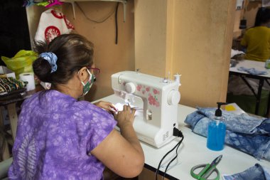 Tayland 'da dikiş makinesinde çalışan yaşlı kadınlar atölyede kumaş maskesi yaparken Coronavirus COVID 19 salgını ve başbakan 2.5. Toz durumu Tayland, Nonthaburi' de