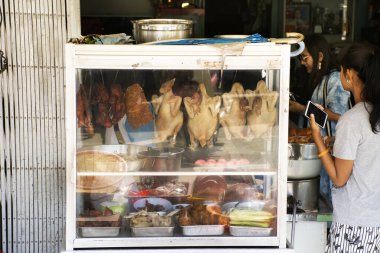 Taylandlı kadın ve gezginler Tayland 'ın Yala kentindeki Betong şehrindeki yerel sokak yemekleri restoranından Hainanese usulü tavuklu pilav ve diğer yiyecekleri alırlar.
