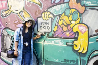 YALA, THAILAND - 16 Ağustos 2019 'da Tayland' ın başkenti Yala 'da, Betong' da sokak sanatının duvarına grafiti resmiyle resim çizen gezgin Tayland 'lı kadınlar ziyaret ediyor ve poz veriyorlar.