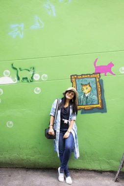 YALA, THAILAND - 16 Ağustos 2019 'da Tayland' ın başkenti Yala 'da, Betong' da sokak sanatının duvarına grafiti resmiyle resim çizen gezgin Tayland 'lı kadınlar ziyaret ediyor ve poz veriyorlar.