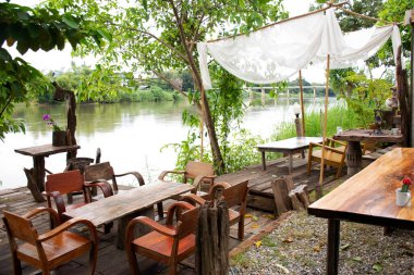 Mae Khlong ya da Meklong nehrinin nehir kıyısındaki teras. Akşamları Ratchaburi, Tayland 'da misafir kullanım hizmeti için antika otel tatil beldesi.