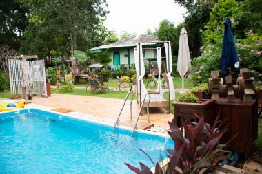 RATCHABURI, THAILAND - 23 Eylül 2019 'da Ratchaburi, Tayland' da Ban Pong şehrindeki tatil beldesinde yüzen ve oynayan insanlar için yüzme havuzları olan manzara bahçesi ve çimenliği