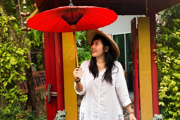 ラチャブリ 9月24日 タイの女性は タイのラチャブリで2019年9月24日に庭で写真を撮るために 竹の帽子と赤い傘でベトナムの民族衣装を着ています — ストック写真
