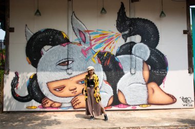 BUENG KAN, THAILAND - 3 Ekim 2019 tarihinde Bueng Kan, Tayland 'da bulunan So Phisai City' deki Yaşam Topluluğu Müzesi 'nde duvar yazısı ile duvar resmi ile poz veren Taylandlı kadınlar,