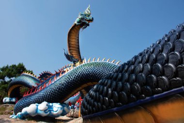 Tayland 'ın Mukdahan kentindeki Mukdahan Milli Parkı' na seyahat ve ibadet eden yabancılar için Wat Roi Phra Phutthabat Phu Manorom 'daki büyük mavi Naka ve beyaz Buda heykeli.