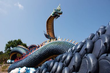 Tayland 'ın Mukdahan kentindeki Mukdahan Milli Parkı' na seyahat ve ibadet eden yabancılar için Wat Roi Phra Phutthabat Phu Manorom 'daki büyük mavi Naka ve beyaz Buda heykeli.