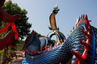 Tayland 'ın Mukdahan kentindeki Mukdahan Milli Parkı' na seyahat ve ibadet eden yabancılar için Wat Roi Phra Phutthabat Phu Manorom 'daki büyük mavi Naka ve beyaz Buda heykeli.