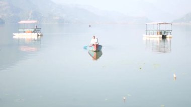 POKHARA, NEPAL - 7 Aralık 2017 'de Pokhara, Nepal' de bulunan Gandaki Pradesh 'in başkentinde Phewa Gölü' nü gezen yabancılar için tahtadan kano botu kullanan Nepalliler