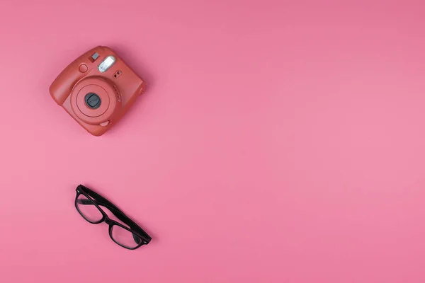 Macchina fotografica e occhiali su sfondo rosa. Concetto moda. Superiore vi — Foto Stock