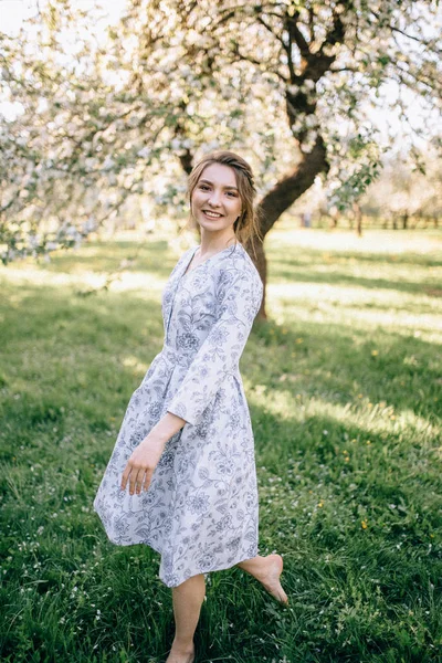 Hermosa joven morena de pie cerca del manzano en un — Foto de Stock