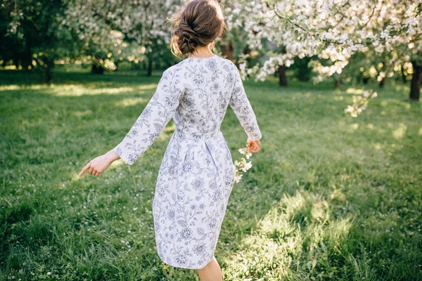 Charming brunette girl in the garden near the flowering tree — Stock Photo, Image