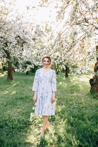 Bela jovem morena mulher de pé perto da árvore da maçã em um — Fotografia de Stock