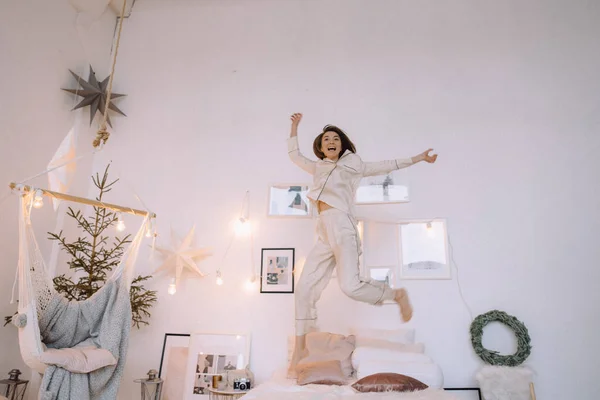 Ung lycklig kvinna hoppar på sängen på morgonen, elegant sovrum, po — Stockfoto