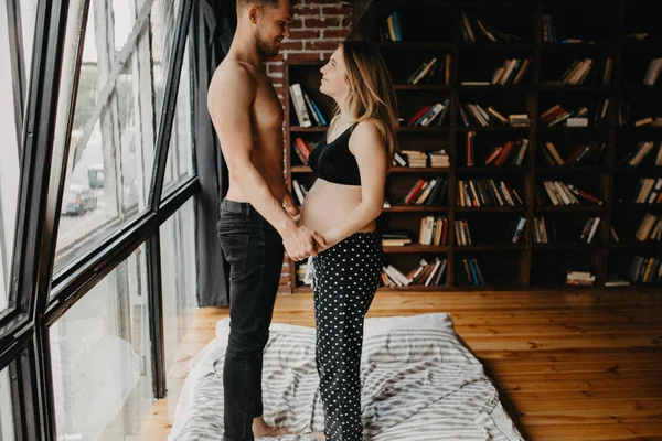 Casal jovem esperando bebê de pé juntos dentro de casa — Fotografia de Stock