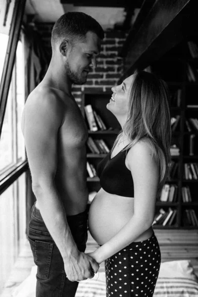 Casal jovem esperando bebê de pé juntos dentro de casa — Fotografia de Stock