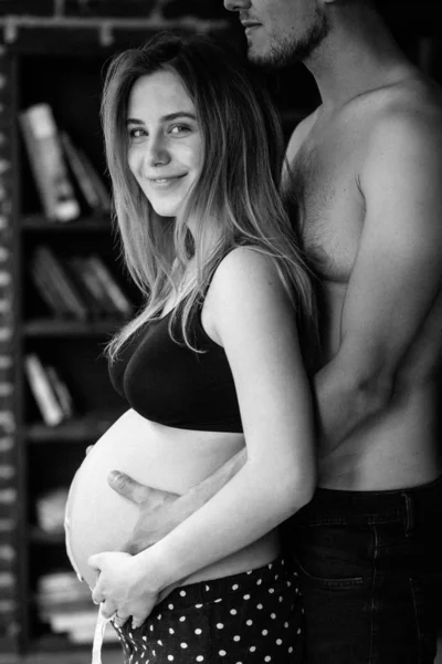 Pareja joven esperando bebé de pie juntos en el interior —  Fotos de Stock