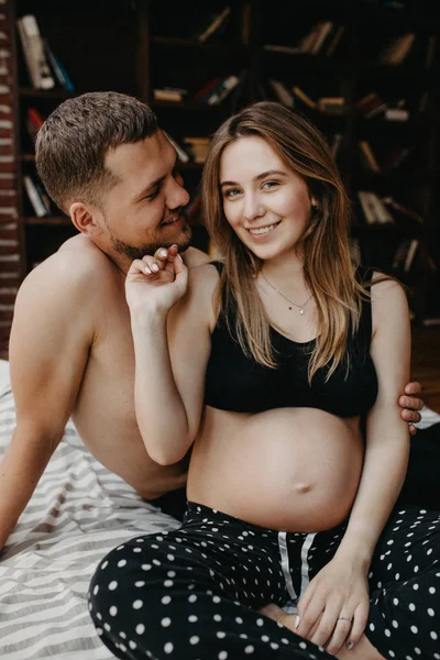 Bella donna incinta e il suo bel marito stanno abbracciando un — Foto Stock