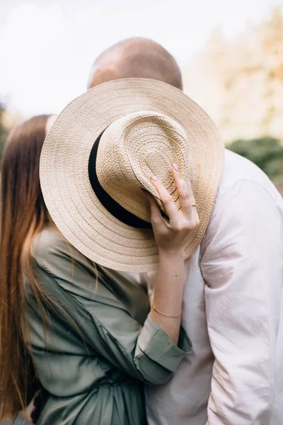 Pärchen küssen sich und bedecken ihr Gesicht mit einem Strohhut. Liebe in ol — Stockfoto