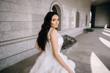 Binanın arka planında güzel beyaz ve uzun bir elbise içinde gelin.