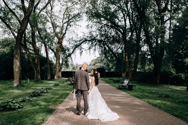 Una hermosa novia está de pie con su espalda en su vestido de novia. Vestido con encaje. La novia feliz está girando —  Fotos de Stock