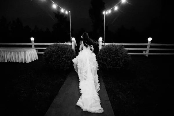 Portrait of young pretty bride in white wedding dress outdoors running away at night — Stock Photo, Image