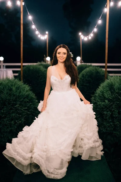 Portrét mladé krásné nevěsty v bílých svatebních šatech venku utíká v noci — Stock fotografie