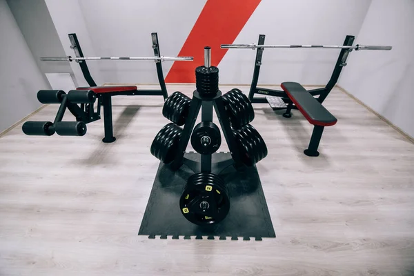 Modern light gym. Sports equipment in gym. Barbells of different weight on rack