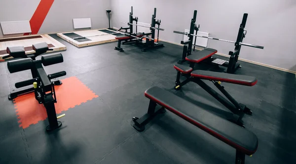 Moderno gimnasio ligero. Equipamiento deportivo en gimnasio. Barras de diferente peso en rack . — Foto de Stock