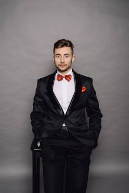 Gri stüdyo arka planında takım elbiseli şık bir iş adamı.