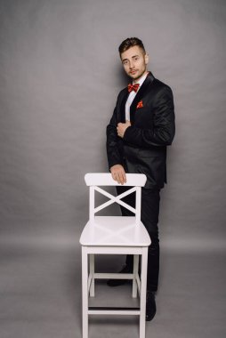 Gri stüdyo arka planında takım elbiseli şık bir iş adamı.