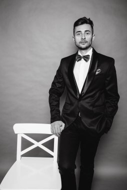 Gri stüdyo arka planında takım elbiseli şık bir iş adamı.